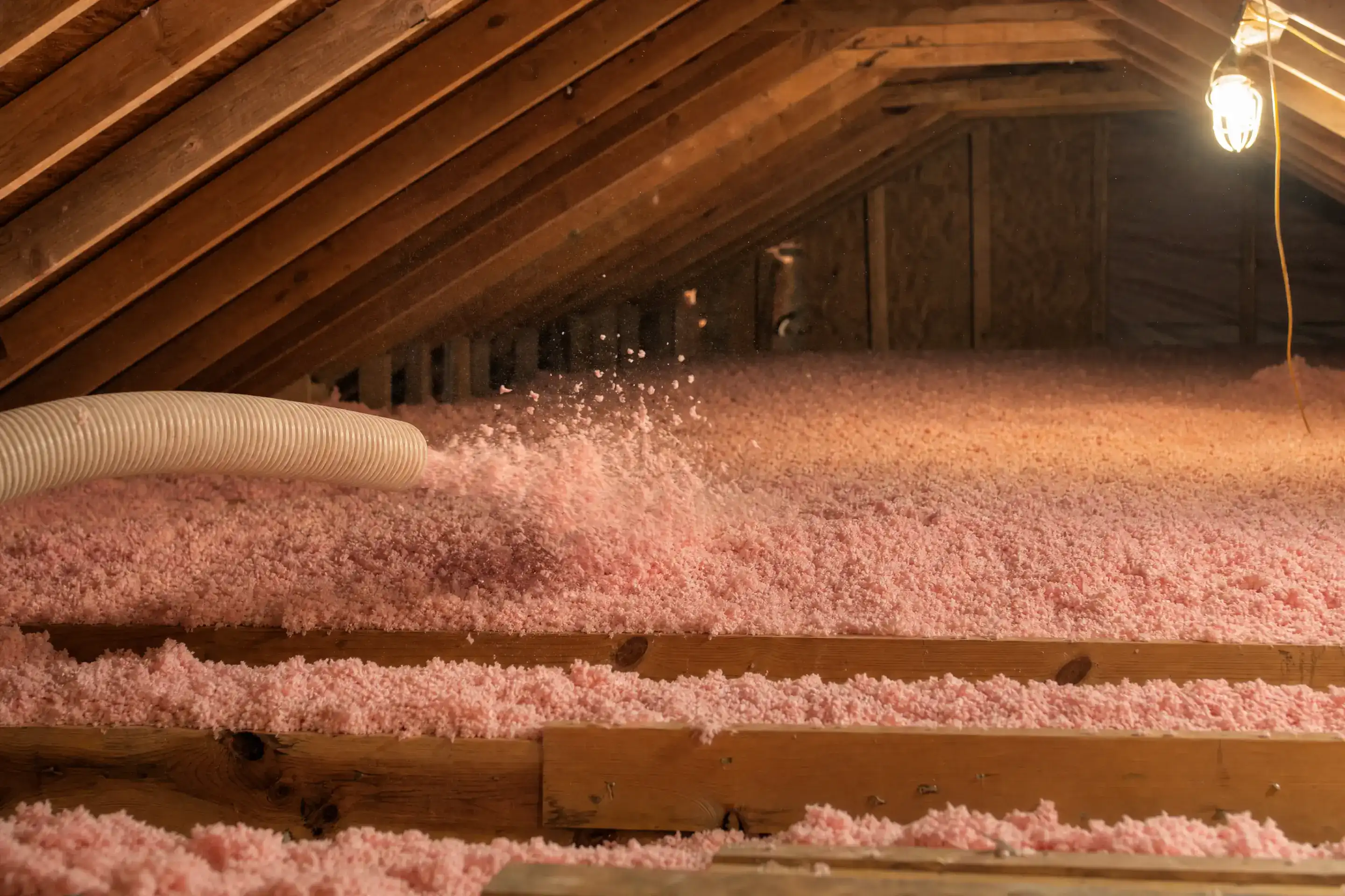 Pink blown-in fiberglass insulation filling a wood-frame attic in a Brevard County home