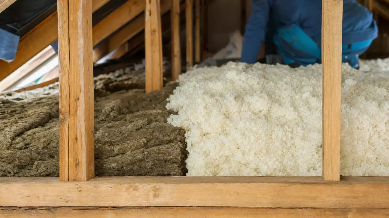 Old compressed grey attic insulation meeting fresh pale new insulation in the same joist bay, the difference in depth clearly visible