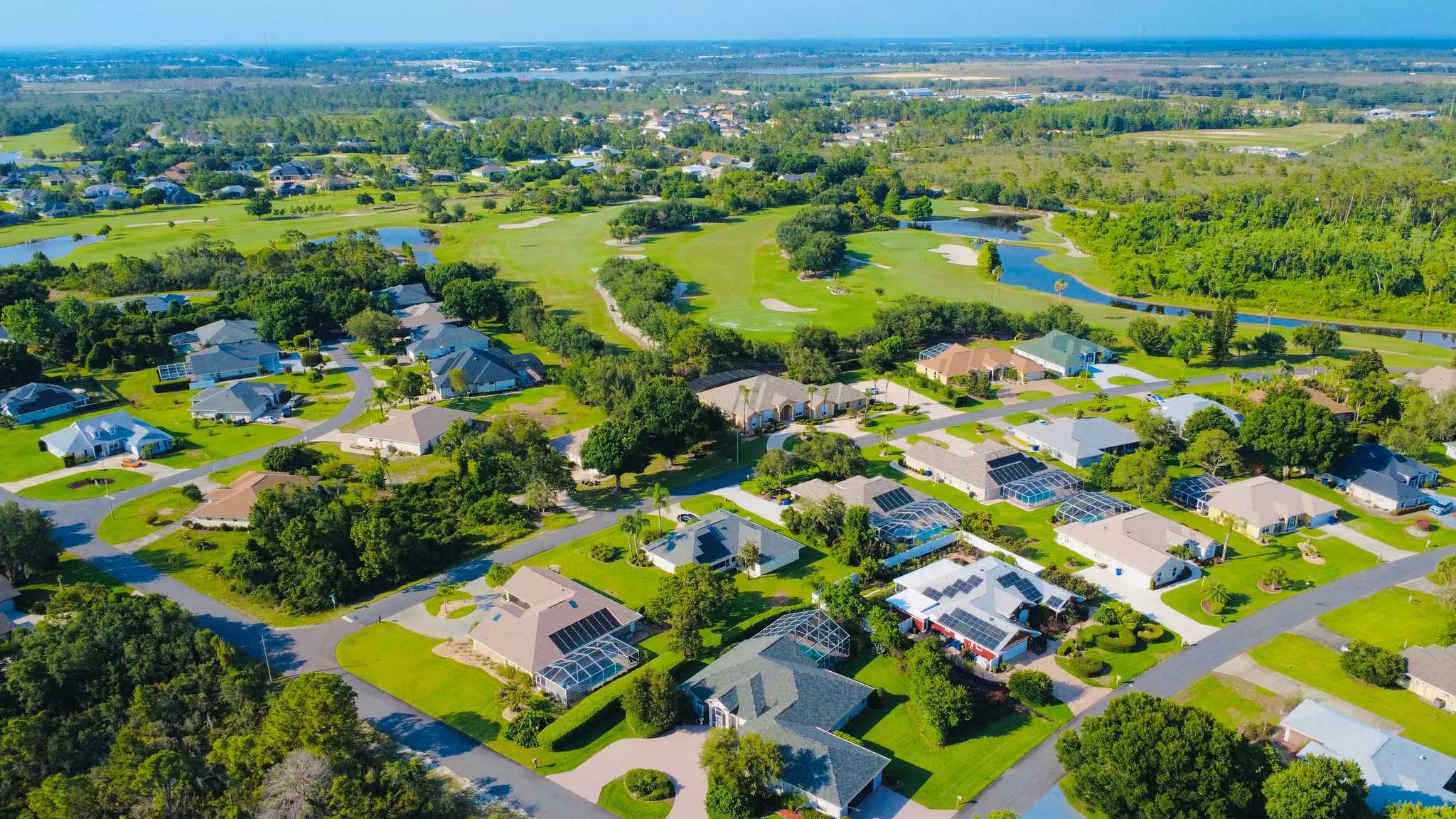 Drone view of a sunny suburban Florida neighborhood with solar panels, representative of Viera, FL's newer construction