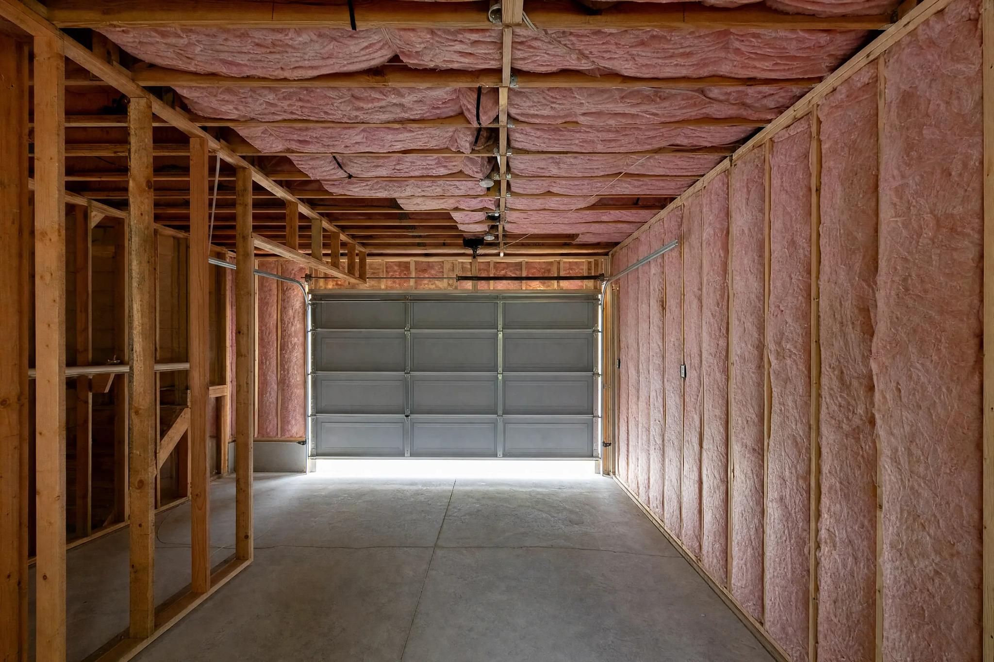 Fiberglass batt insulation fitted between wall studs and ceiling joists in a garage